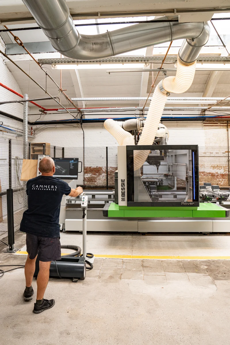 Een vakman bedient de houtbewerkingsmachine in het atelier van Cammers