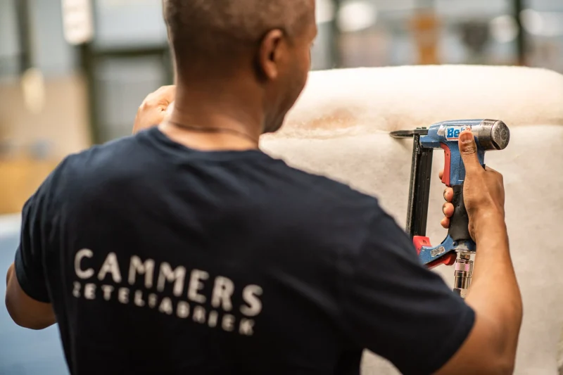 Een stoffeerder werkt de bekleding met de hand af
