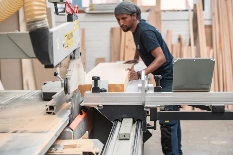 Medewerker zaagt een massief houten zetelframe op maat in het atelier in Mechelen